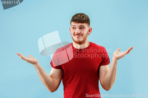 Image of Beautiful male half-length portrait isolated on blue studio backgroud. The young emotional surprised man