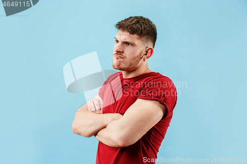 Image of The young emotional sad angry man on blue studio background