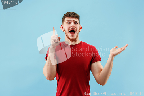 Image of The young attractive man looking suprised isolated on blue