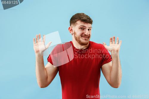 Image of Beautiful male half-length portrait isolated on blue studio backgroud. The young emotional surprised man