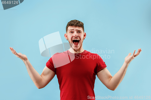 Image of The young attractive man looking suprised isolated on blue