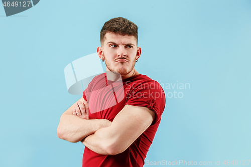 Image of The young emotional sad angry man on blue studio background