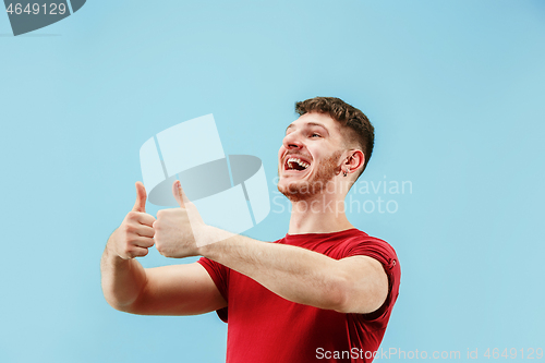 Image of The happy businessman standing and smiling against blue background.