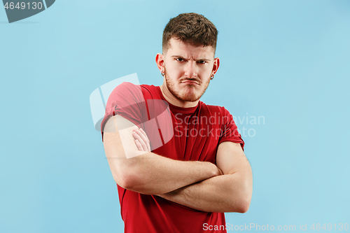 Image of The young emotional sad angry man on blue studio background