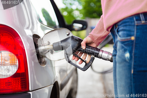 Image of Lady pumping gasoline fuel in car at gas station.