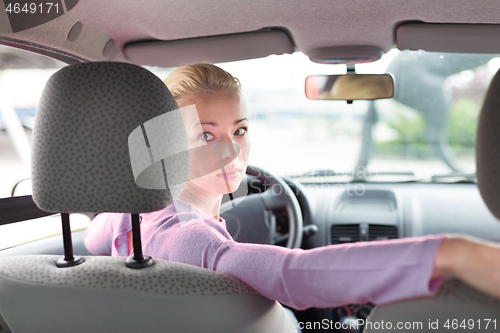 Image of Female driver looking back while reversing in car.