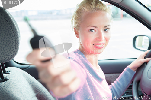 Image of Female driver showing car keys. Young female driving happy about her new car or drivers license.