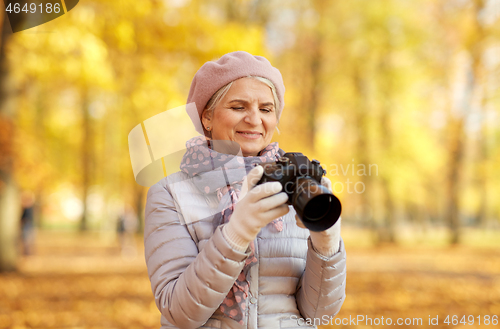 Image of senior woman with photo camera at autumn park