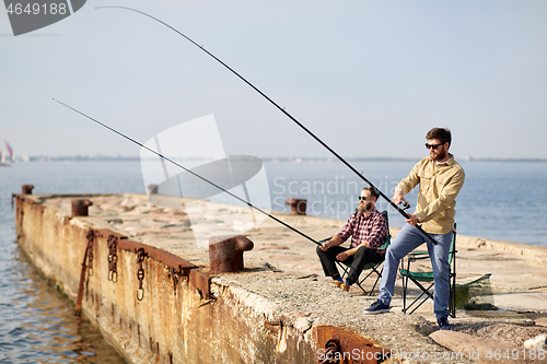 Image of happy friends with fishing rods on pier