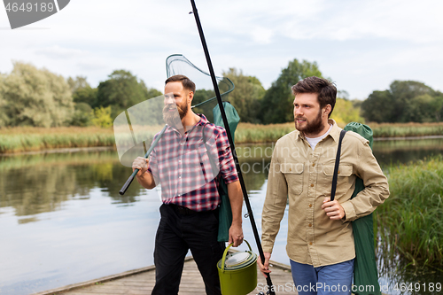 Image of male friends with net and fishing rods on lake