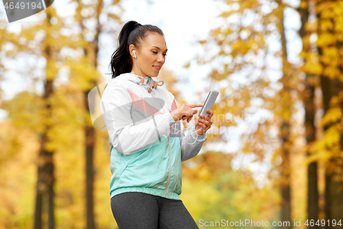 Image of woman in autumn park and listening to music