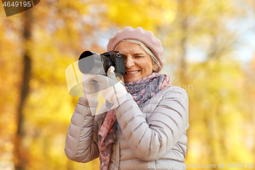 Image of senior woman with photo camera at autumn park