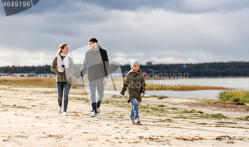 Image of happy family walking along autumn beach