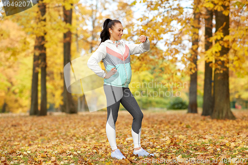 Image of woman looking at fitness tracker in autumn park