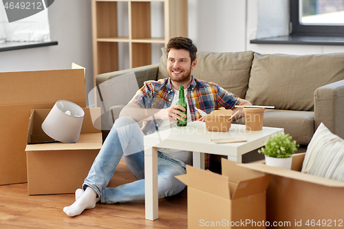 Image of smiling man drinking beer and eating at new home