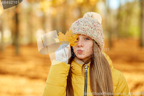 Image of portrait of girl with maple leaf at autumn park