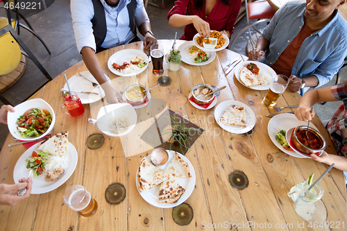 Image of international friends eating at restaurant