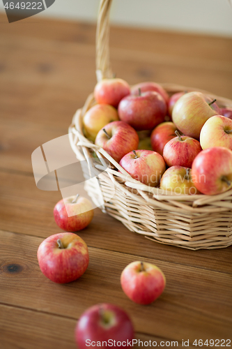 Image of ripe apples in wicker basket on wooden table