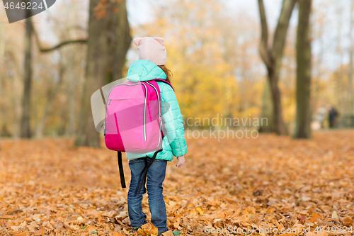 Image of little girl with school bag at autumn park