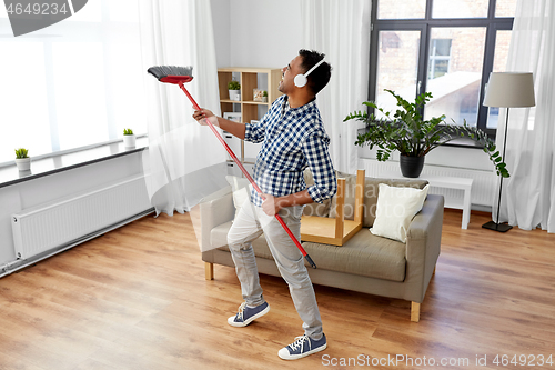 Image of man with broom cleaning and having fun at home