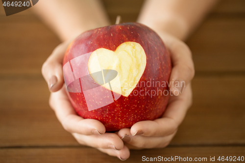 Image of close up of hands holding apple with carved heart