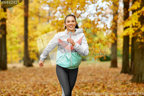 Image of young woman running in autumn park