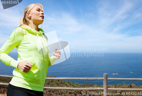 Image of woman with earphones running at seaside