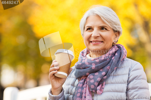 Image of senior woman drinking coffee in autumn park