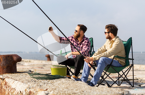 Image of friends fishing and taking selfie by smartphone