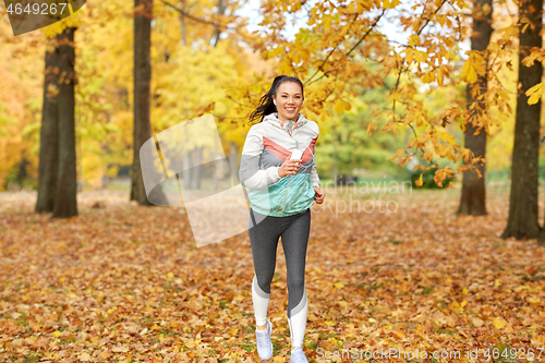 Image of woman running in park and listening to music