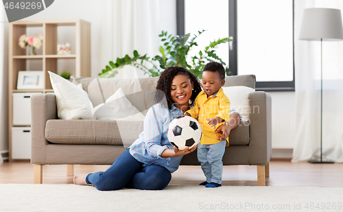 Image of mother and baby playing with soccer ball at home