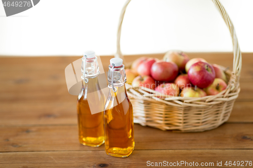 Image of apples in basket and bottles of juice on table