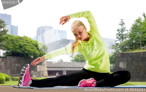 Image of woman stretching on exercise mat at city park