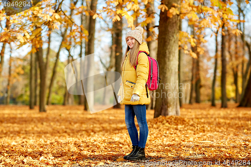 Image of happy student girl with schoolbag at autumn park