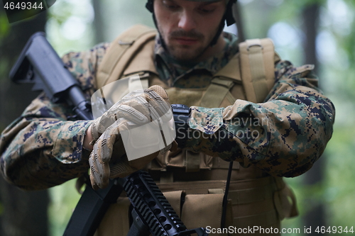 Image of soldier preparing tactical and commpunication gear for action ba