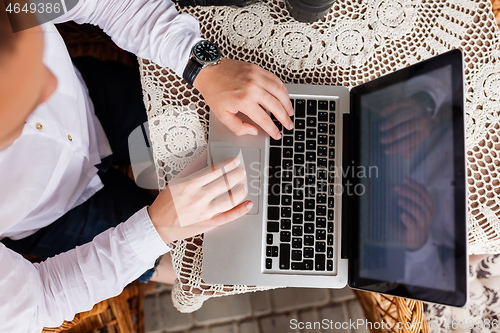 Image of man working with laptop computer and sitting on sofa