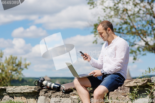 Image of Handsome businessman with laptop talking on the phone