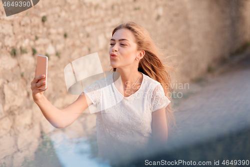 Image of Girl take selfie from hands with phone on summer city