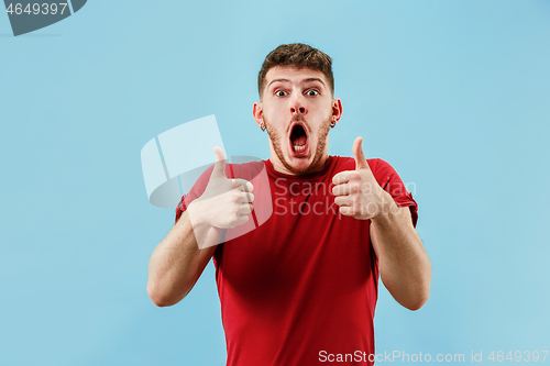 Image of The happy businessman standing and smiling against blue background.