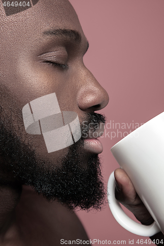 Image of African man with cup of tea, isolated on pink background