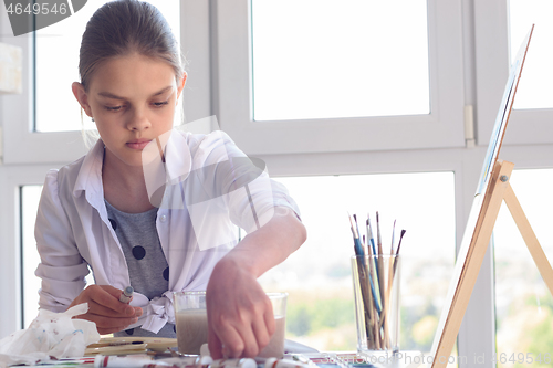 Image of Girl examines paint in the workplace in the studio