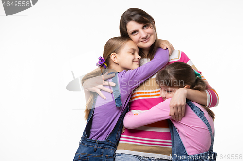 Image of Children hug their beloved mom, mom happily looks in the frame