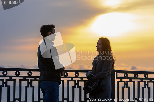 Image of Young couple by the sea at sunset communicates while respecting social distance