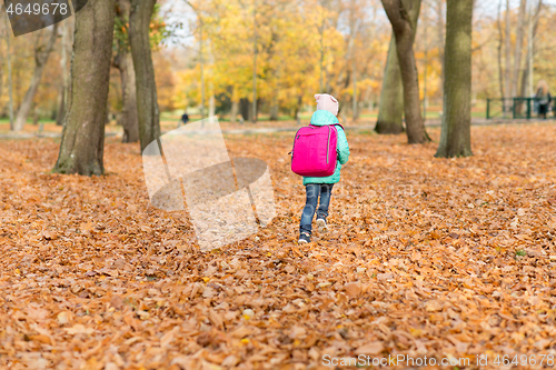 Image of little girl with school bag at autumn park