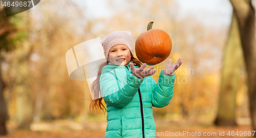 Image of happy girl playing with pumpkin at autumn park