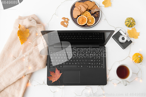 Image of laptop, tea, camera, autumn leaves and sweater