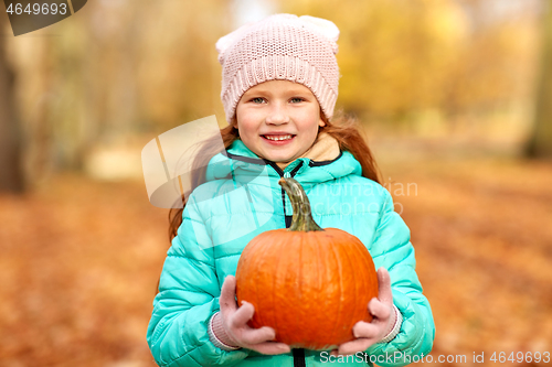 Image of happy redhead girl with pumpkin at autumn park