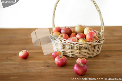 Image of ripe apples in wicker basket on wooden table