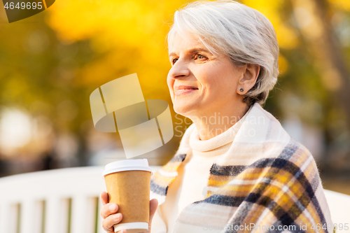 Image of senior woman drinking coffee in autumn park