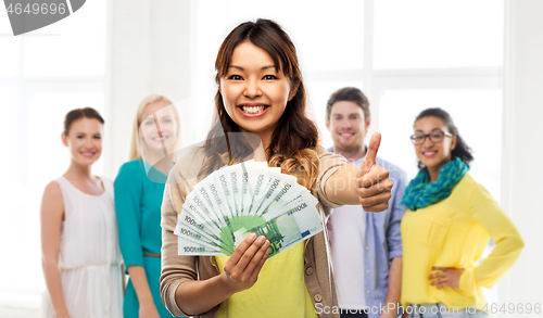Image of asian woman with money showing thumbs up